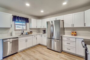 A modern kitchen with white cabinets, a stainless steel refrigerator, and a dishwasher. - Near River! Home w/ Fenced Yard in Bullhead City (Bullhead City)