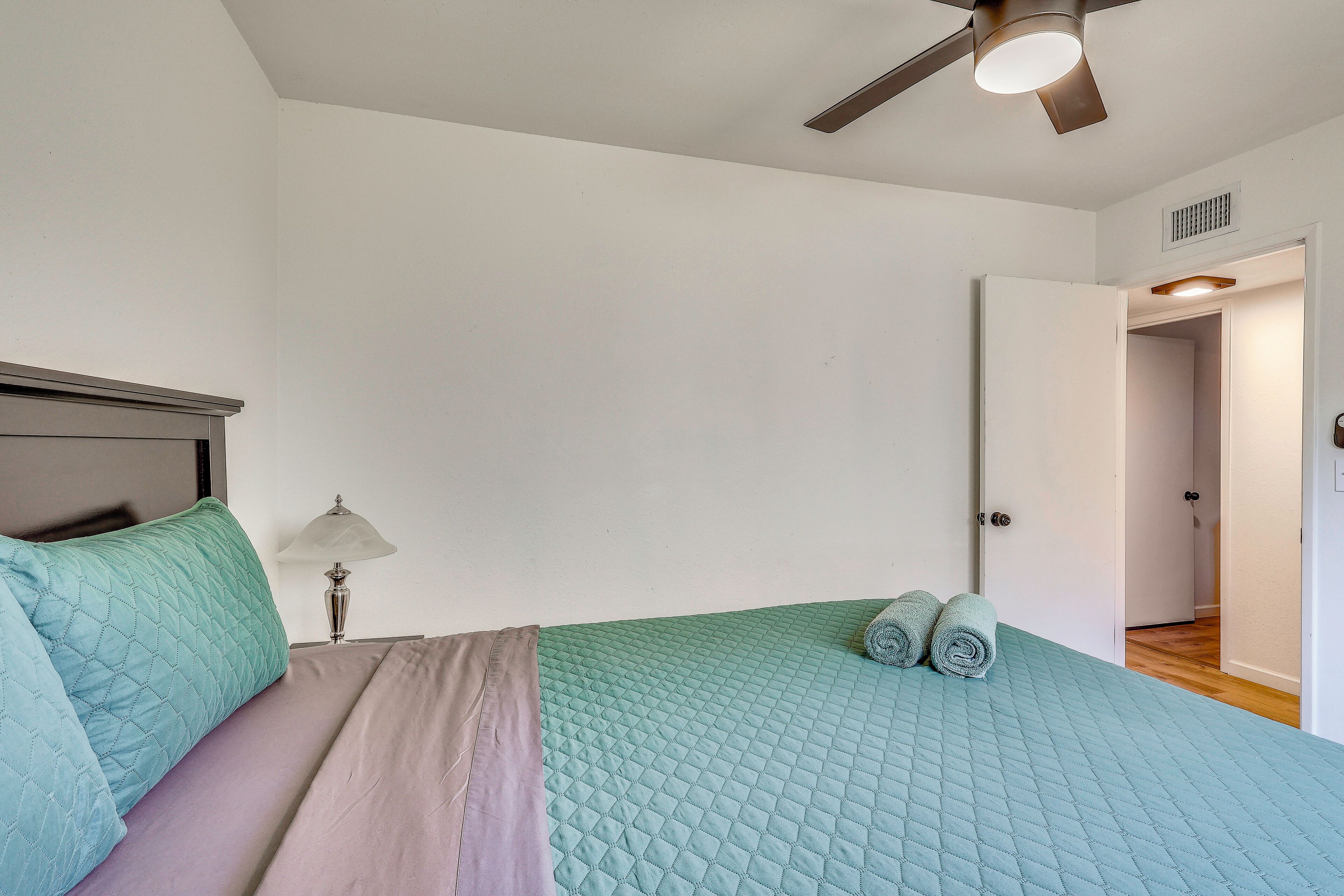 Ein Schlafzimmer mit einem Bett, einem Deckenventilator, einem Nachttisch und einer Lampe.