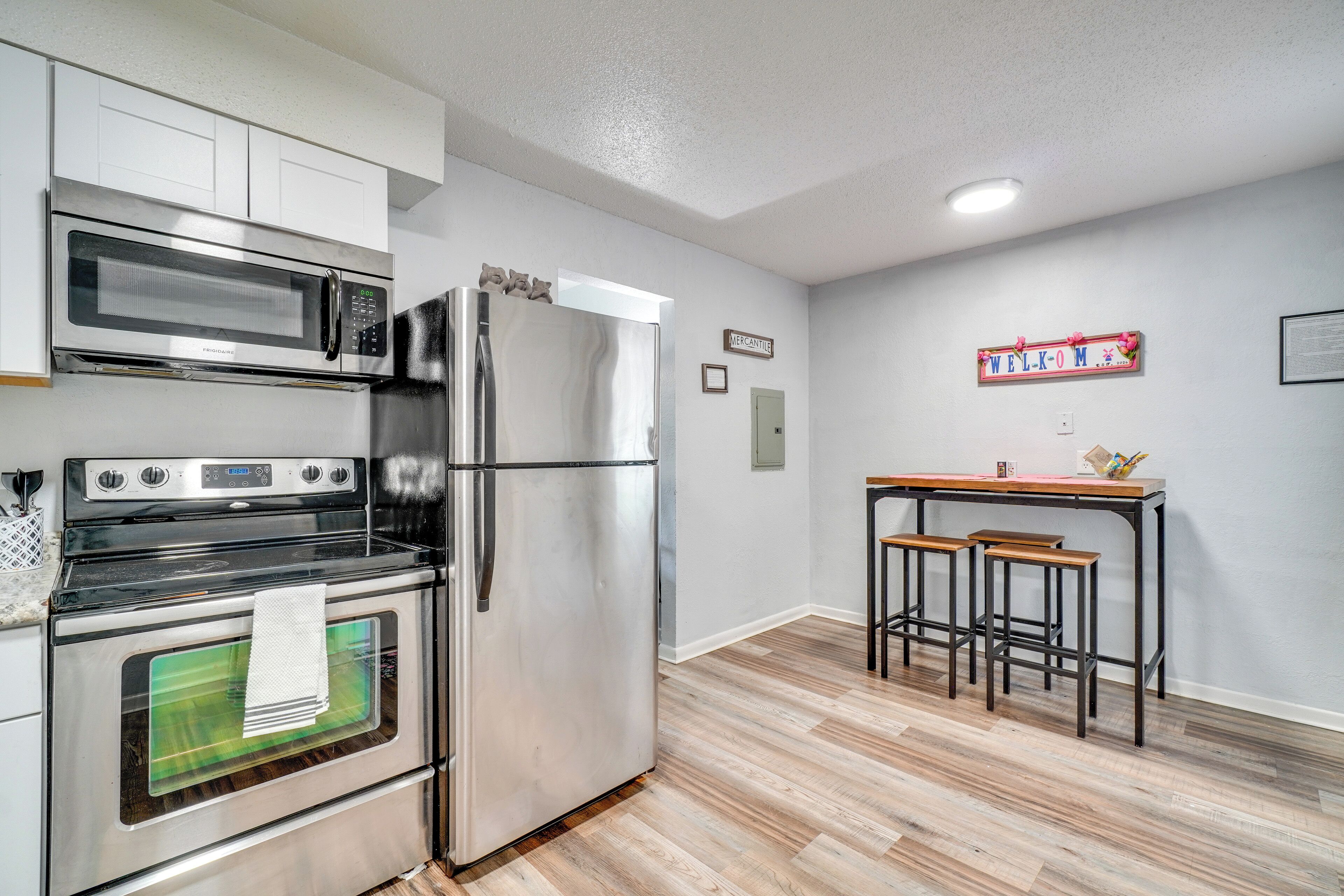 A kitchen with stainless steel appliances, a wooden bar counter, and a 'WELCOME' sign.