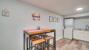 A kitchen with a bar stool, a washing machine, and a refrigerator.