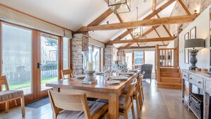 Une cuisine spacieuse avec des poutres en bois, une grande table à manger et une vue sur l’extérieur.