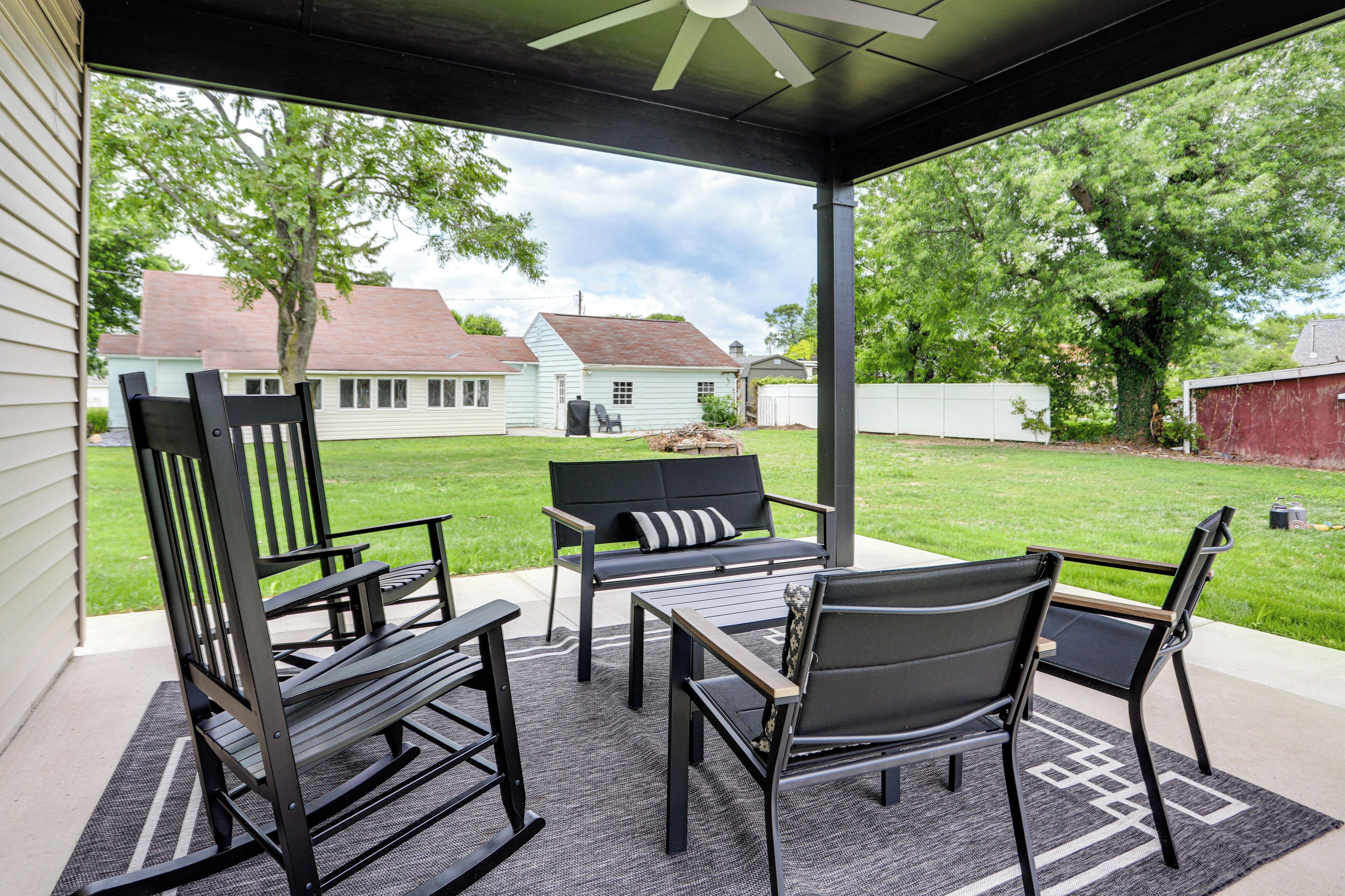 A covered patio with outdoor furniture, a ceiling fan, and a view of a residential neighborhood.