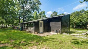 A single-story building with a garage door, a front porch, and a small front yard with grass and rocks.