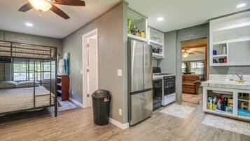 A compact kitchen with a refrigerator, oven, and a dining area with a sofa.