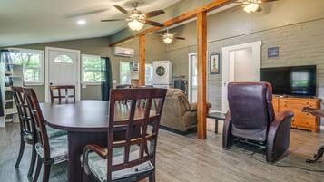 A spacious living area with a dining table, chairs, a sofa, a recliner, a TV, and a ceiling fan.