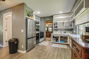 A modern kitchen with stainless steel appliances, wooden flooring, and built-in cabinetry. - ATV and Boating Base! Home Under 1 Mi to Grand (Disney)