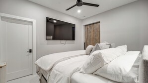 A bedroom with a bed, a ceiling fan, a mounted TV, and a wooden door. - Trackside Luxury at Atlanta Motorsports Park (Dawsonville)