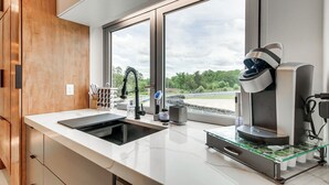 A modern kitchen with a large window, a coffee machine, and a sink. - Trackside Luxury at Atlanta Motorsports Park (Dawsonville)