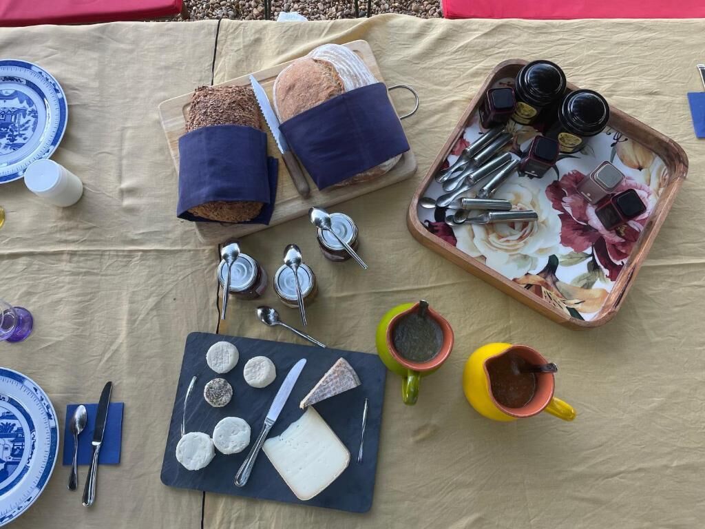 Un'apparecchiatura da picnic con pane, formaggio, marmellate e condimenti su una tovaglia.