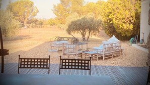 A deck with outdoor furniture, a small table, and a bench.