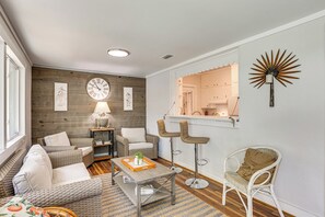 A living room with a sofa, chairs, a table, a lamp, a clock, and a decorative wall piece. - Palm Cottage: Walk to Darien Waterfront & Fort (Darien)