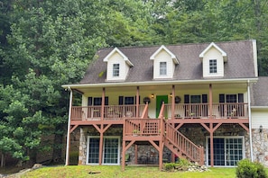 A two-story house with a balcony, stone foundation, and a green door. - Riverfront Home w/ Mtn Views, Near Blue Ridge Pkwy (Canton)
