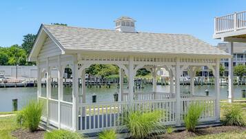 A white gazebo with a peaked roof, surrounded by water and greenery.