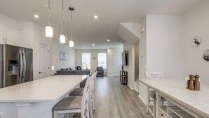 A modern kitchen with a central island, bar stools, a dining table, and a built-in oven. - Walk to Cambridge Waterfront: Townhome w/ Deck (Cambridge)