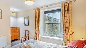 A bedroom with a bed, a dresser, a chair, a window with curtains, and a lamp. - 2 Bed in Hexham (oc-50500) (Bellingham)