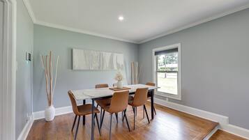 A dining area with a table, chairs, a vase, and a window.
