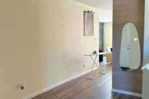Ett modernt hotellrum med trägolv, ett litet bord med en stol, en stor spegel och en dörr som är dekorerad med en surfbräda.