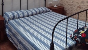 Quarto com uma cama, mesa de cabeceira, abajur e parede decorada com palmeiras.