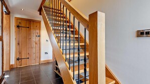 A wooden staircase with a metal railing, a door with a handle, and a wall-mounted light switch. - 3 Bed in Bromyard (oc-50513) (Pencombe)