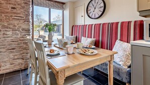 A cozy dining area with a wooden table, chairs, and a bench. A large wall clock is visible. - 3 Bed in Bromyard (oc-50513) (Pencombe)