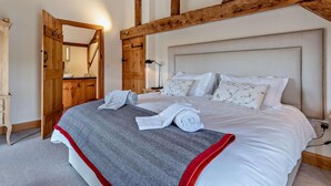 A bedroom with a large bed, wooden beams, a wooden wardrobe, and a mirror. - 3 Bed in Bromyard (oc-50513) (Pencombe)