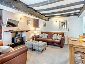 Ein gemütliches Wohnzimmer mit Kamin, Ledersofa und Fernseher.