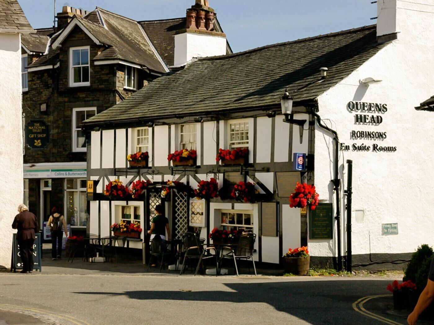 A traditional Tudor-style building with a sign for 'Queens Head Robinsons En Suite Rooms.'