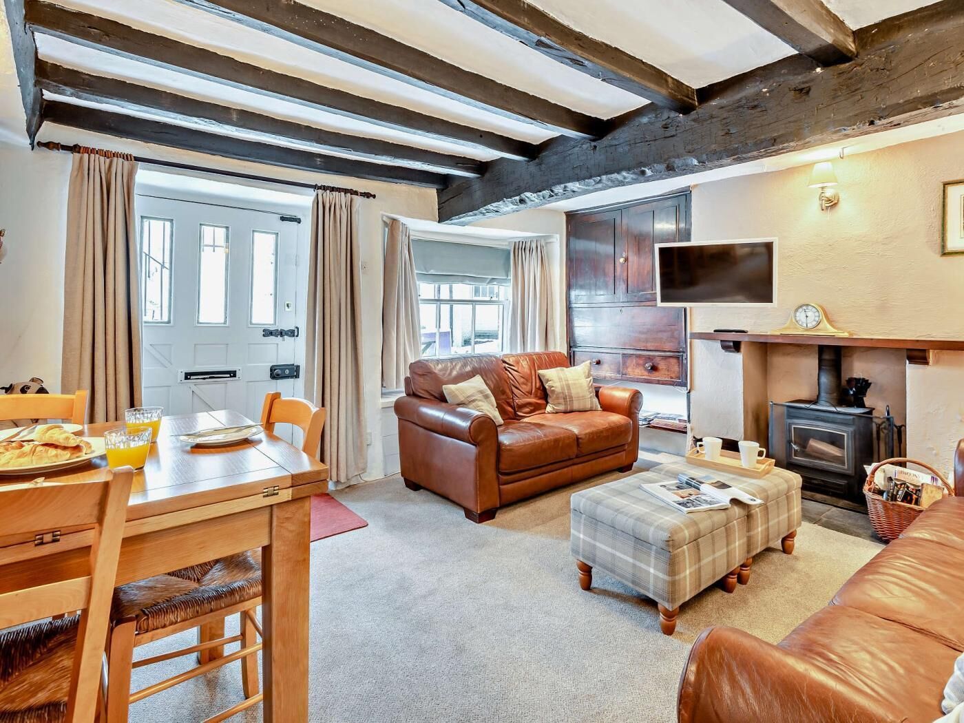 A cozy living room with a fireplace, a sofa, a dining table with chairs, and a television.