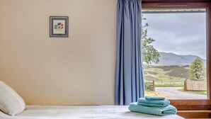 A bedroom with a bed, a window with a view of a landscape, and a framed picture on the wall. - 3 Bed in Dunkeld (oc-50619) (Amulree)