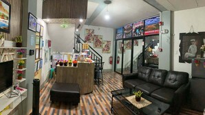 Una sala de estar con televisión, un sofá, una mesa de centro y una cocina con mostrador y taburetes.