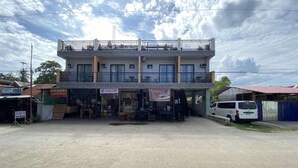 Un edificio de dos pisos con un balcón, una tienda y una furgoneta estacionada.
