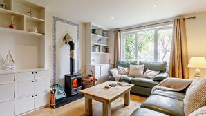A cozy living room with a fireplace, a sofa, a coffee table, and a bookshelf. - 4 Bed in Bude (oc-50591) (Bude)