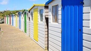 A row of colorful beach huts with white walls and doors in various colors. - 4 Bed in Bude (oc-50591) (Bude)