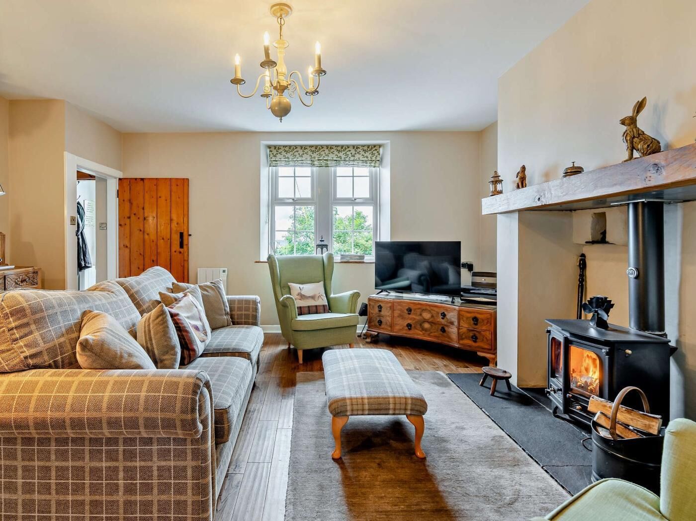 Een knusse woonkamer met een bank, fauteuil, televisie en een houtkachel.