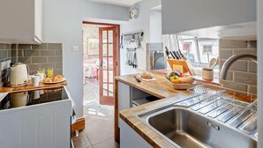 Une cuisine moderne avec un plan de travail en bois, un évier en acier inoxydable et une vue sur l’extérieur.