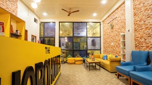 A hotel lobby with a reception desk, seating area, and a brick wall.