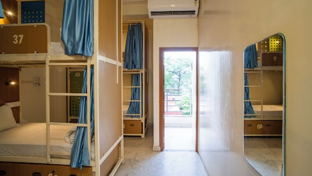 A dormitory room with bunk beds, a door leading outside, and an air conditioning unit above the door.