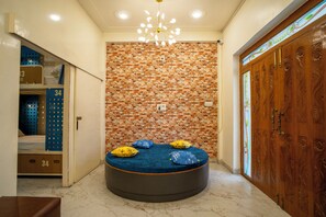A room with a brick wall, a round bed with pillows, a wooden door, and a ceiling light fixture. - The Hobohomes Varanasi - Hostel & Private Rooms Near Sarnath (Varanasi)