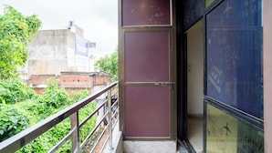 A narrow stairway leading to a door with a metal frame, a metal railing on the left, and a window with graffiti on the right.