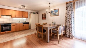 Une cuisine moderne avec des meubles en bois, une table à manger avec des chaises et un lustre.