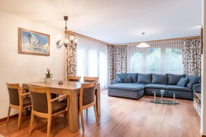 Ein Wohnzimmer mit Esstisch, Stühlen, einer Couch und einer Pendelleuchte.