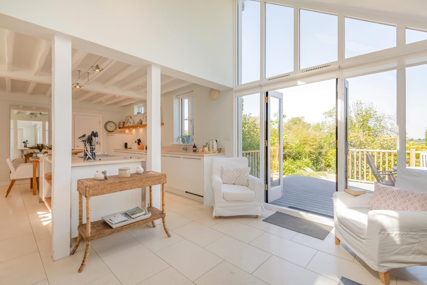 A spacious living area with a large sliding glass door leading to a balcony, a kitchen with white cabinetry, and a dining area with a white table and chairs.