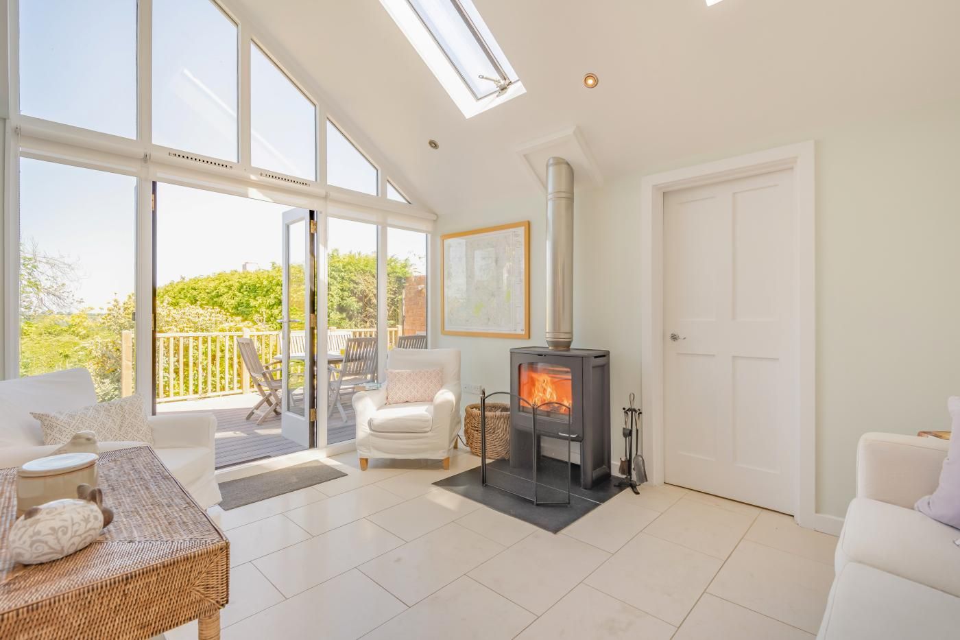 Een ruime woonkamer met een groot raam, een open haard en een balkon met tuinmeubilair.