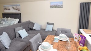 A cozy living room with a grey sofa, a wooden coffee table, and a breakfast setup. - 1 Bed in Lymington (oc-50723) (Sway)