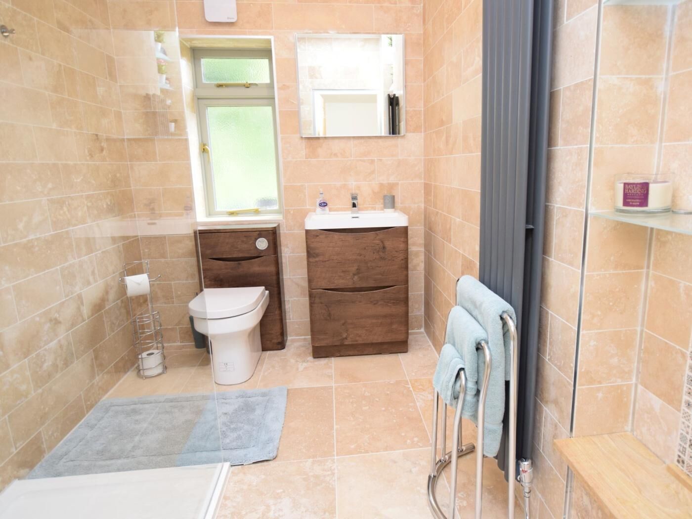 Une salle de bain comprenant des toilettes, un lavabo, un miroir, un porte-serviettes et un espace douche.