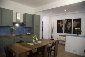 Una cocina moderna con armarios verdes, una mesa de comedor de madera y un banco. Hay tres mapas del mundo enmarcados en la pared.