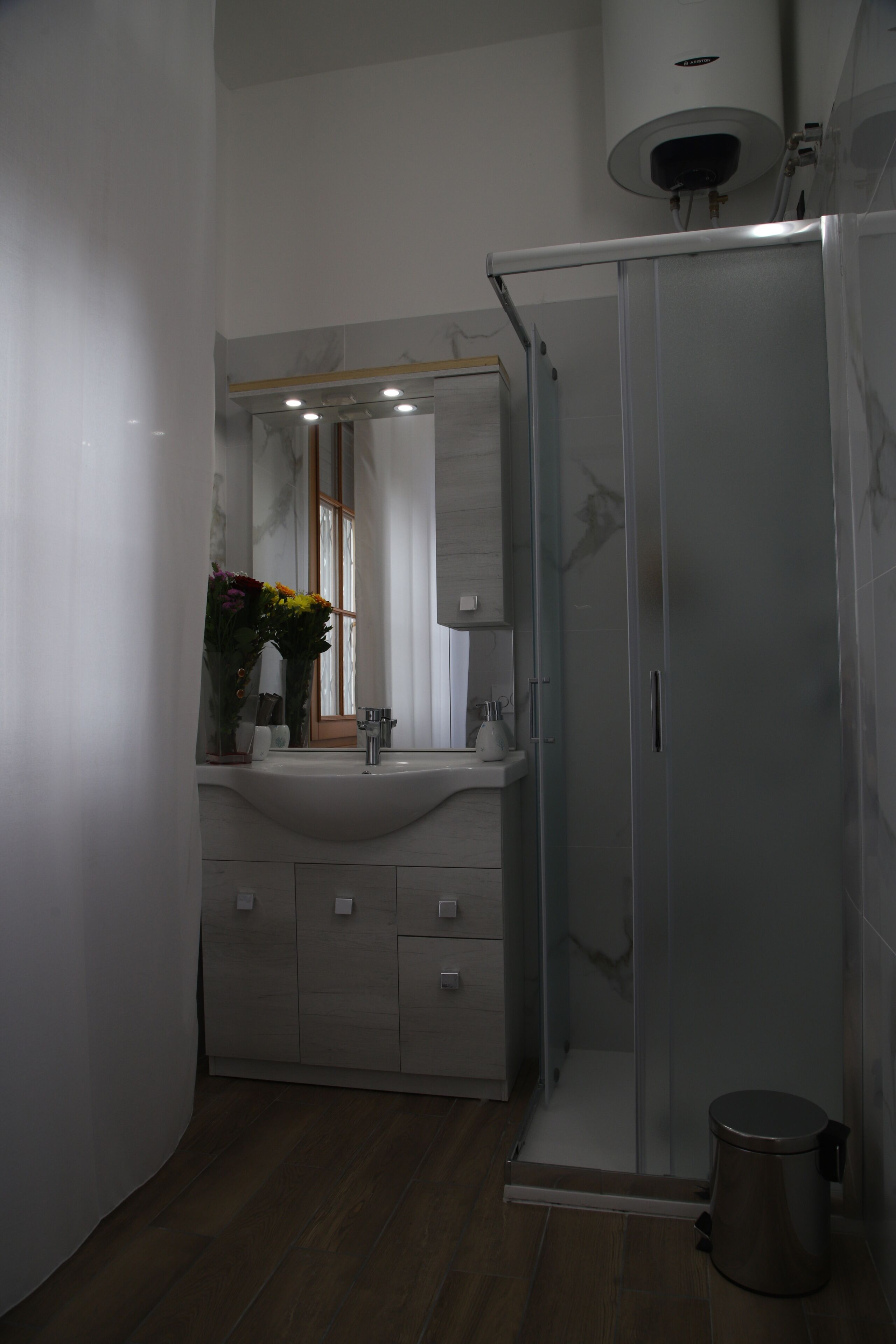 A modern bathroom with a glass shower enclosure, a white sink, and a mirror above the vanity.