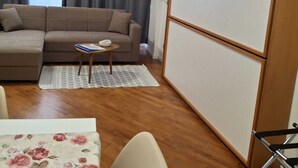 A living room with a sofa, a small table, a TV, and a wooden cabinet. - LA TORRETTA (Savona)