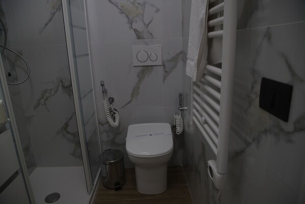 Un baño pequeño con inodoro, ducha y barra para toallas.