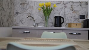 A modern kitchen with a marble backsplash, a black coffee maker, and a vase of yellow tulips on the counter. - LA TORRETTA (Savona)
